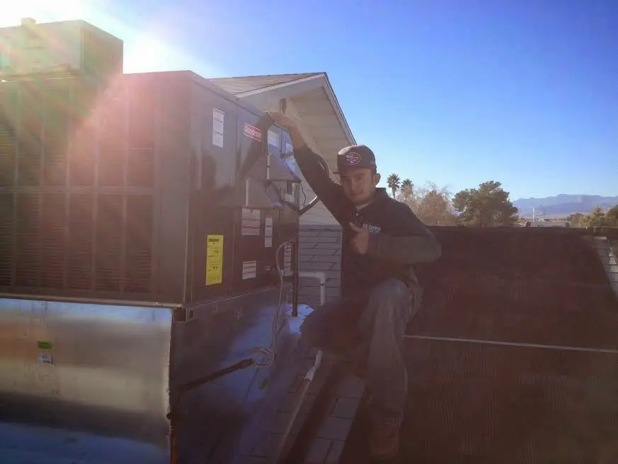 HVAC technician performing AC Tune-Up on a rooftop unit in Brigham City