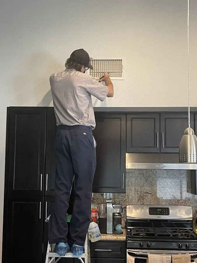 Technician inspecting an air vent during HVAC service in Brigham City
